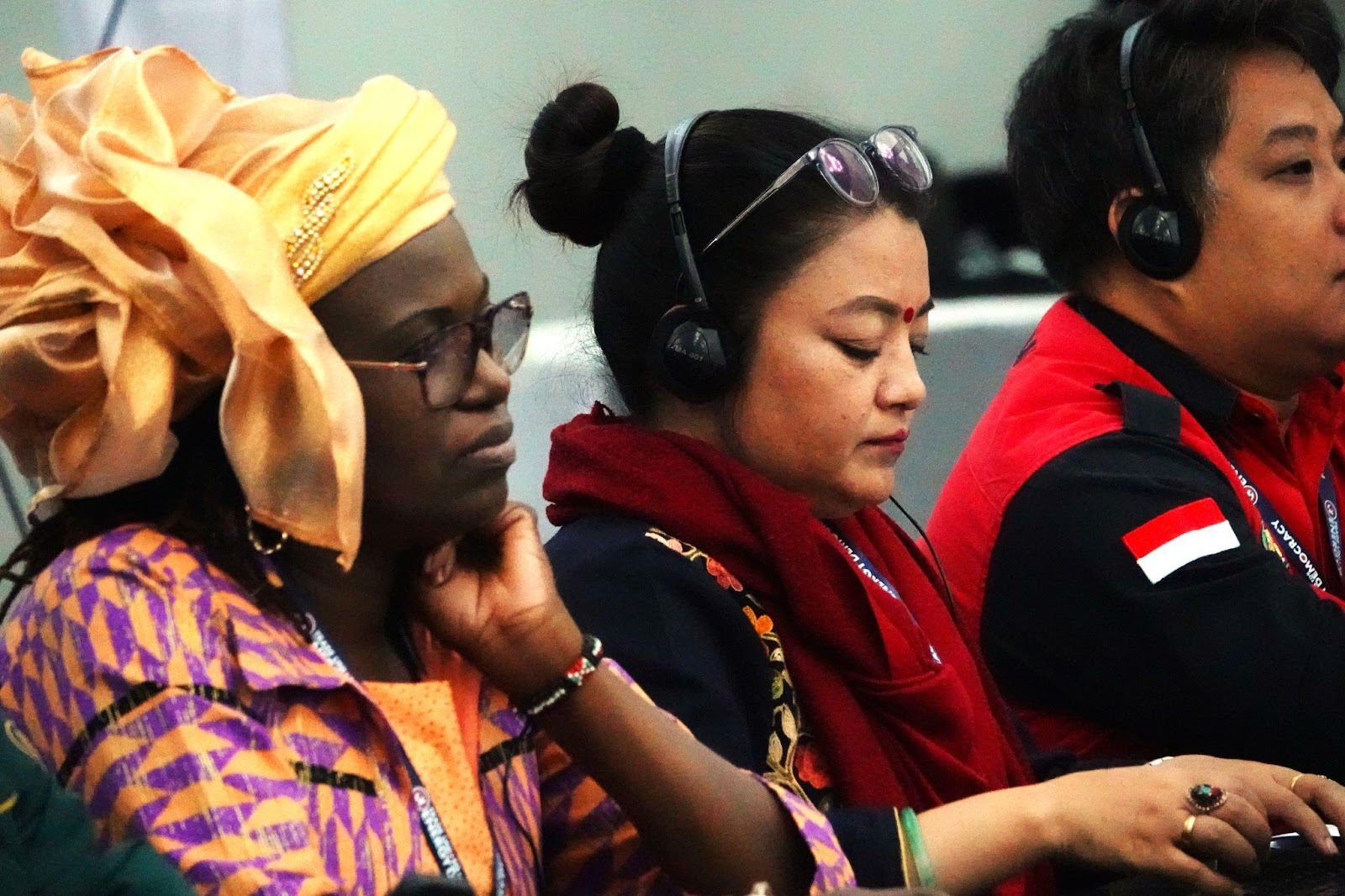 TUED delegates from Africa, Asia, and Latin America listening with translation headphones during a plenary session