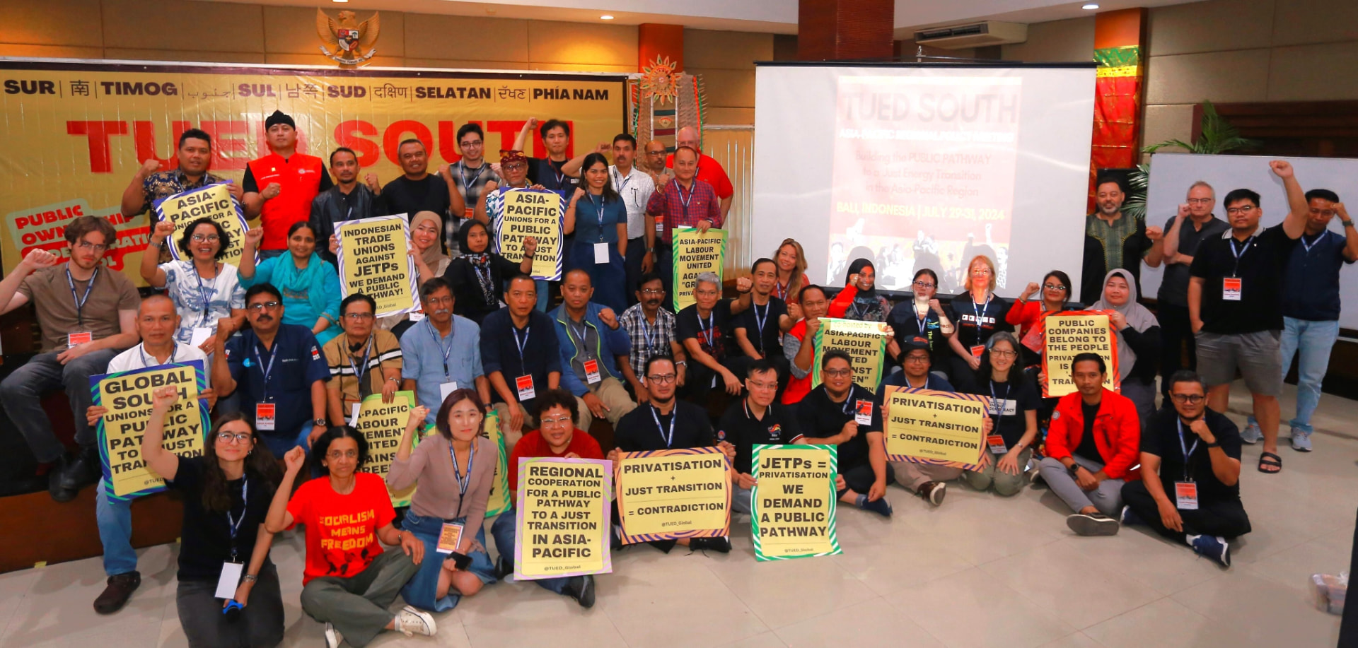 Group photo of TUED South Asia-Pacific delegates in Bali holding signs against privatisation and for a public pathway to a just transition